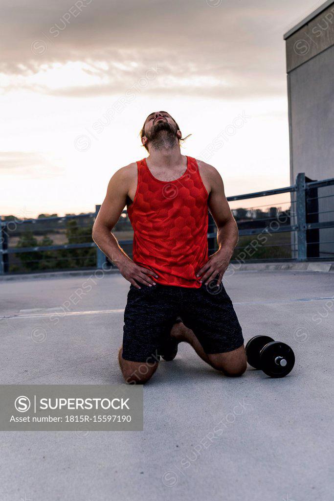 Exhausted athlete kneeling on ground after workout - SuperStock