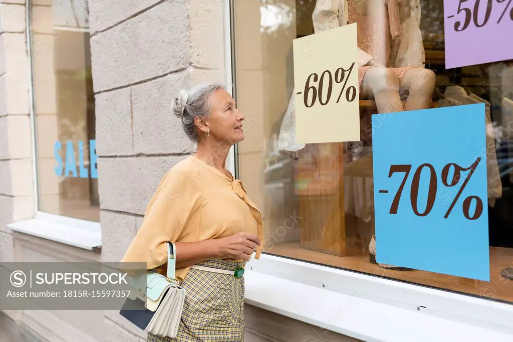 Smiling senior woman looking in shop window of a boutique