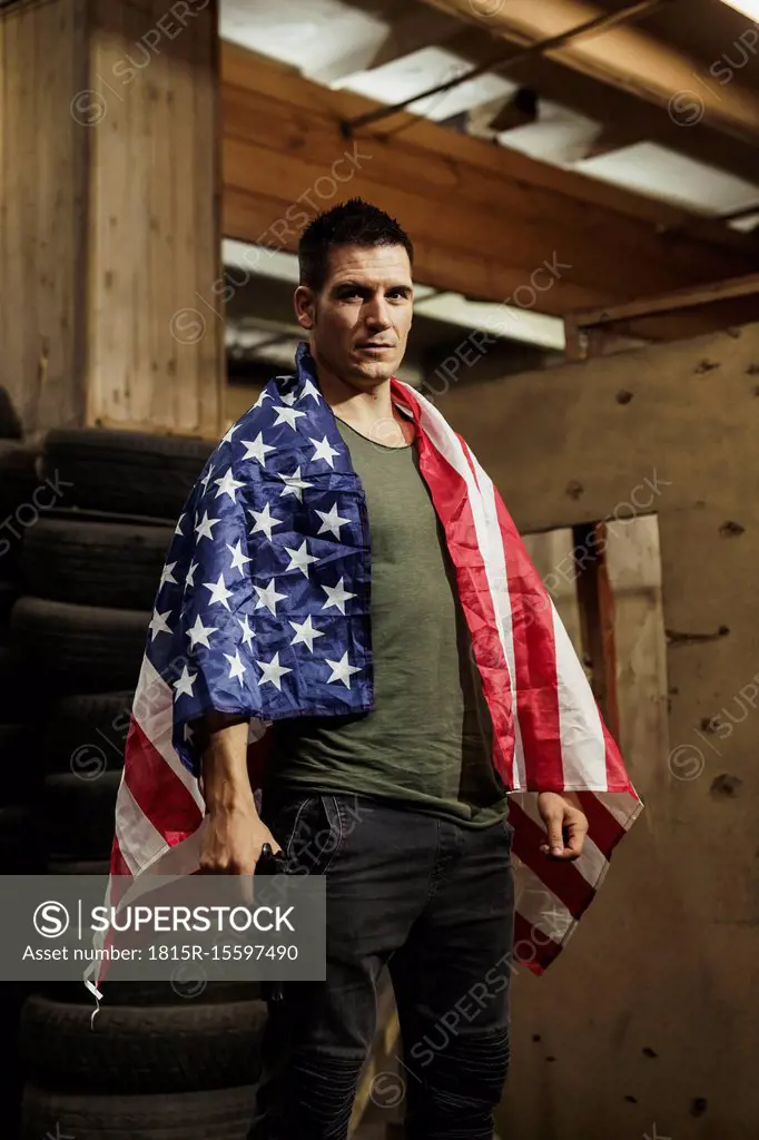 Portrait of man wearing American flag holding a gun