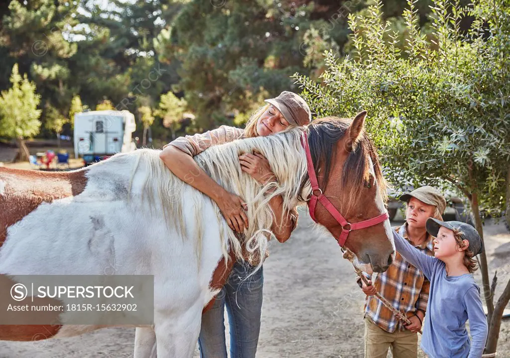 Woman with two sons cuddling with a horse