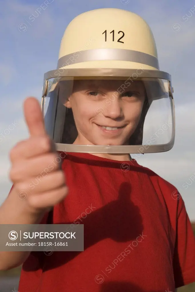 Boy (10-13) wearing helmet, thumb up, smiling