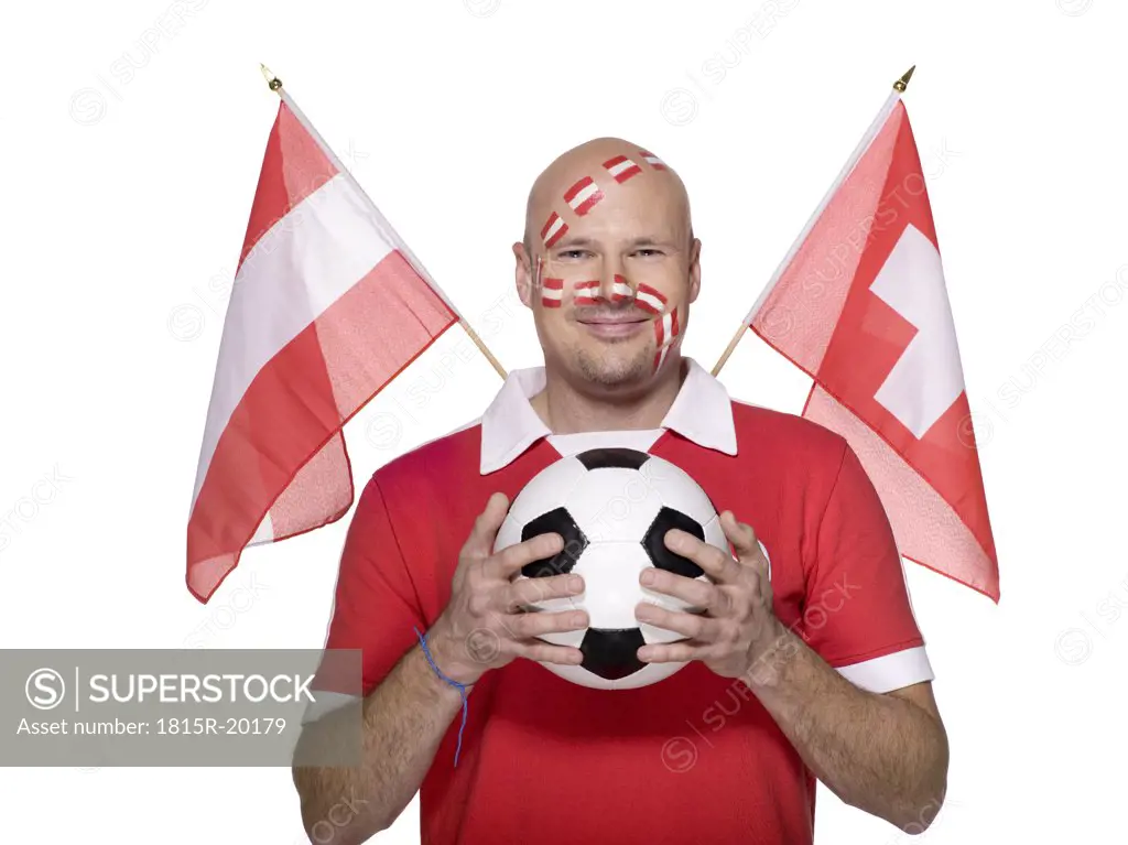 Man with Austrian flag painted on face, holding football, flags aside