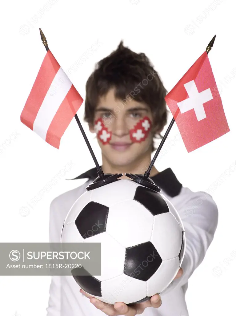 Man with Swiss flag painted on face holding football, Austrian and Swiss flag aside