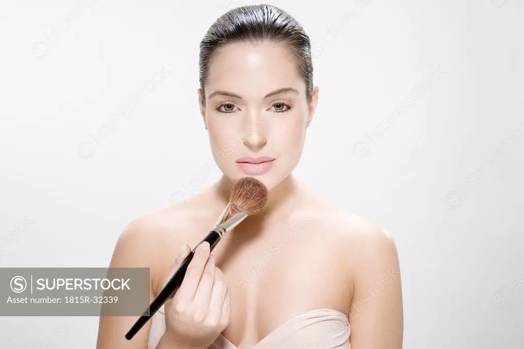 Young woman using make up brush, portrait