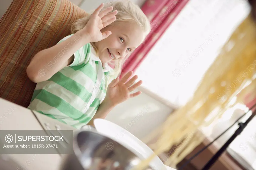 Girl (8-9) sitting at dining table