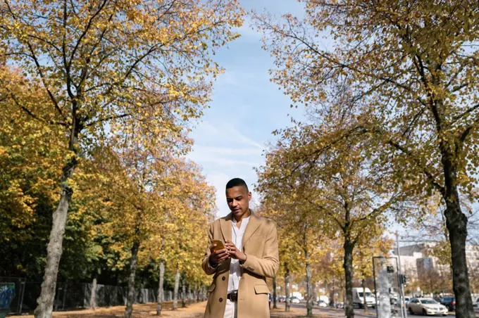 Portrait of businessman using smartphone in autumn