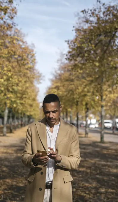 Portrait of businessman using smartphone in autumn