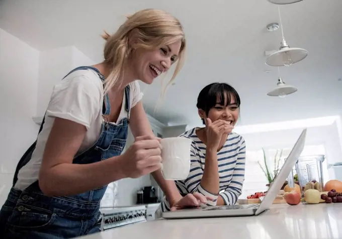 Two friends preparing fresh smoothie, chopping fruits in the kitchen