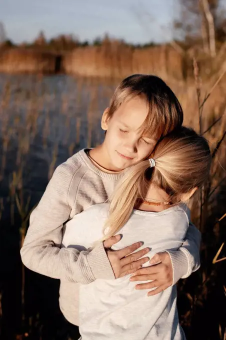 Portrait of boy hugging his little sister in autumnal nature