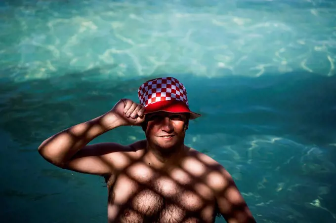 Portrait of overweight man with hat in pool in shady area