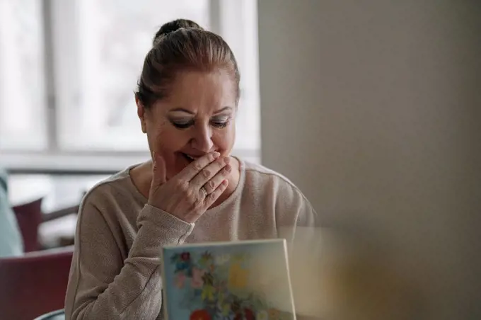 Happy senior woman looking in jewelry box at home