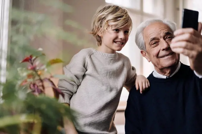 Happy grandfather and grandson taking a selfie at home