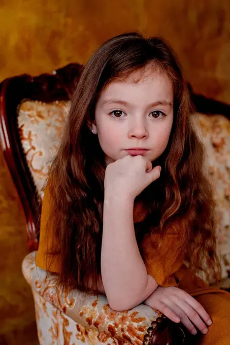 Portrait of little girl sitting on lounge chair