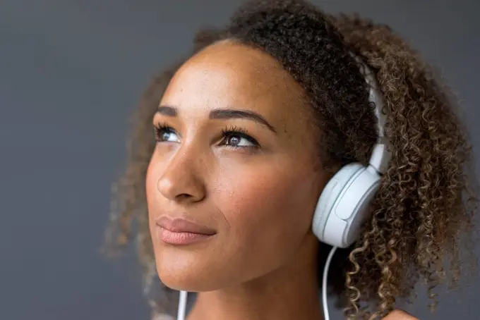 Portrait of young woman with white headphones looking up