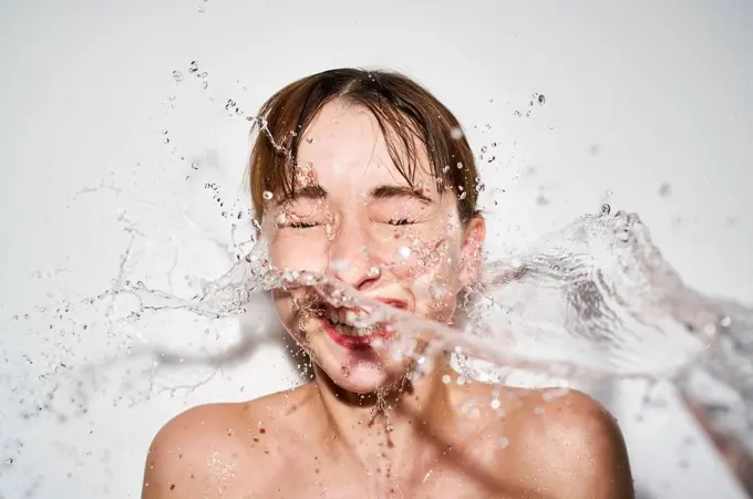 Portrait of laughing young woman with splashing water