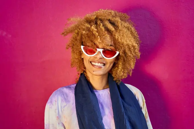 Portrait of happy woman before a pink wall