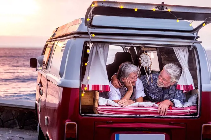 Senior couple traveling in a vintage van, lying in boot