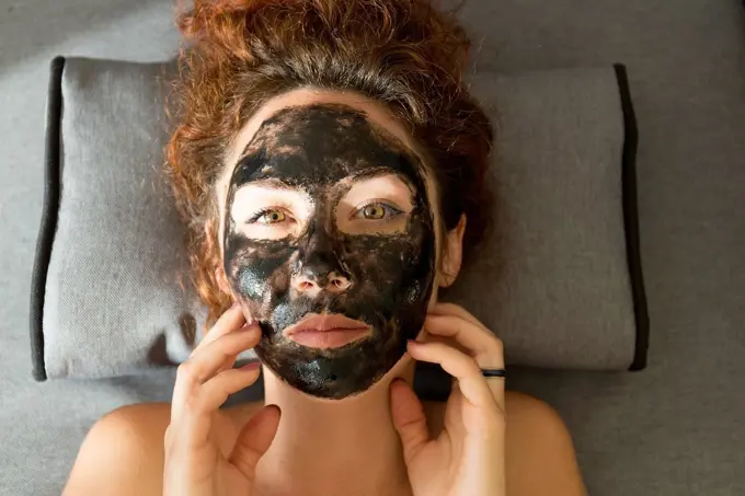 Portrait of young woman lying down wearing facial mask