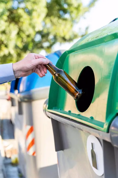 Close-up of man putting bottle into bottle bank