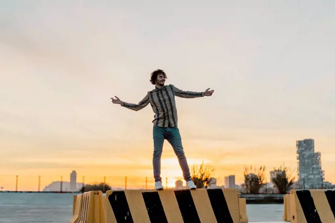 Happy man standing on barrier enjoying sunset, Barcelona, Spain