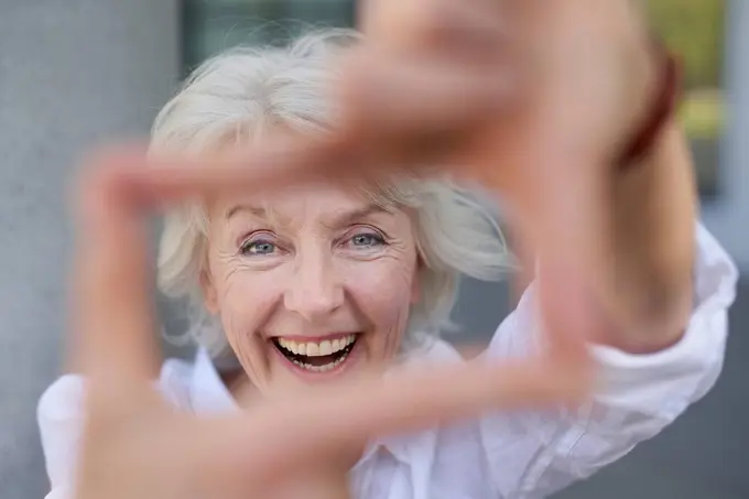 Portrait of laughing mature woman shaping frame with her fingers