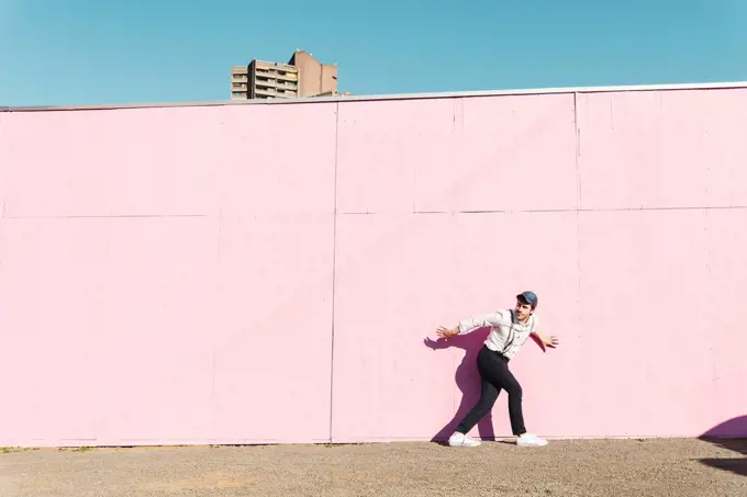 Young man in front of pink construction barrier, trying to escape