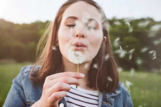 Portrait of teenage girl blowing blowball