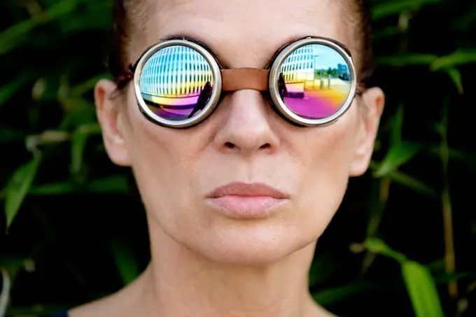 Mature woman wearing welder's goggles in front of an office building