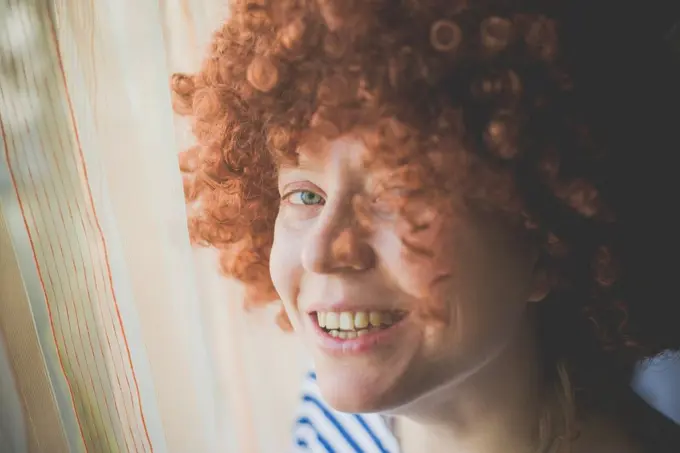 Portrait of smiling woman wearing a red curly carnival wig