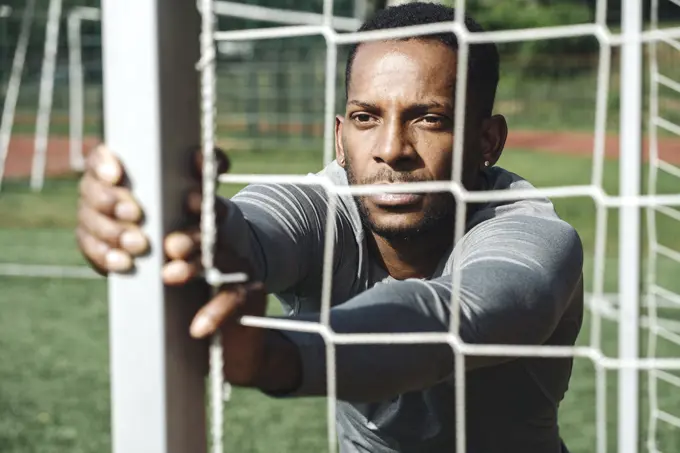 Portrait of sportsman stretching exercise behind net