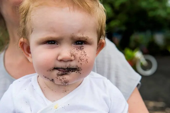 French Polynesia, Taharuu Beach, baby girl's face full of black sand