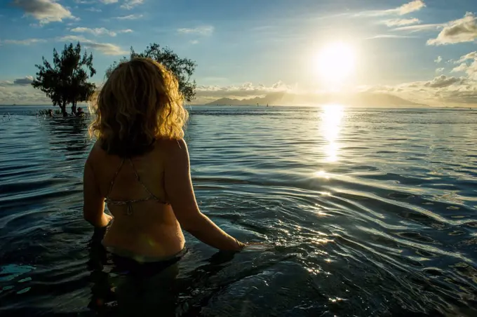 French Polynesia, Tahiti, Papeete, woman enjoying the sunset in an infinity pool