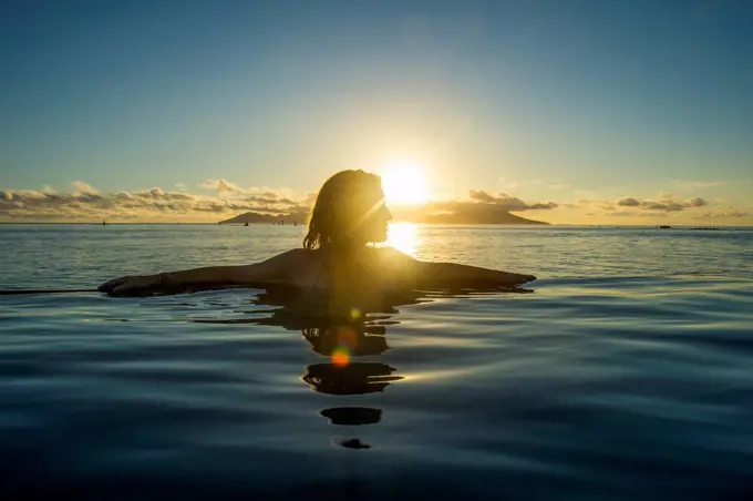 French Polynesia, Tahiti, Papeete, woman enjoying the sunset in an infinity pool