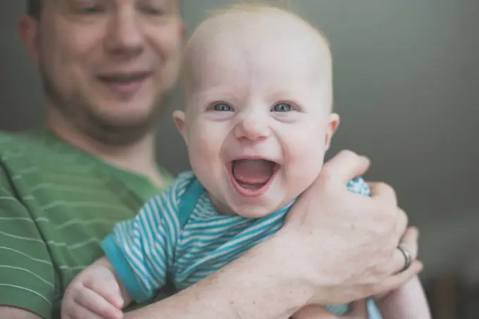 Father holding his laughing baby daughter