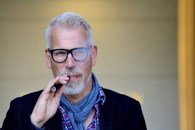 Portrait of a mature man, smoking electronic cigarette