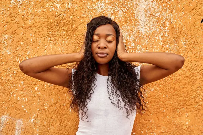 Portrait of young woman covering ears with her hands