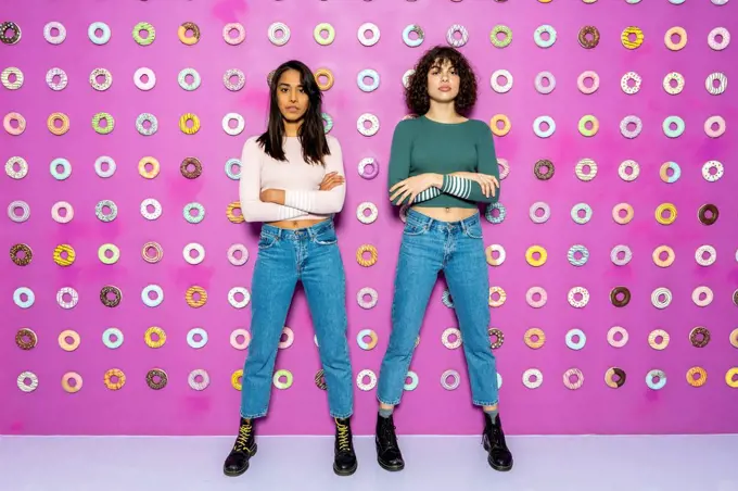 Two young women posing at an indoor theme park with donuts at the wall