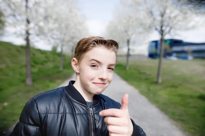 Teenage boy in a park giving thumbs up