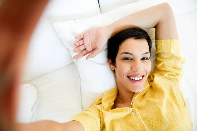 Portrait of smiling young woman lying in bed