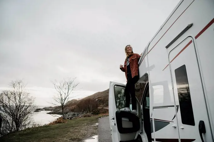 UK, Scotland, Highland, happy young woman at a camper van