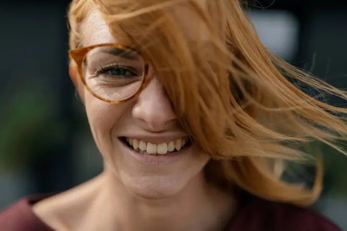 Portrait of happy young woman with glasses and windswept hair