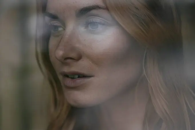 Close-up of young woman behind windowpane