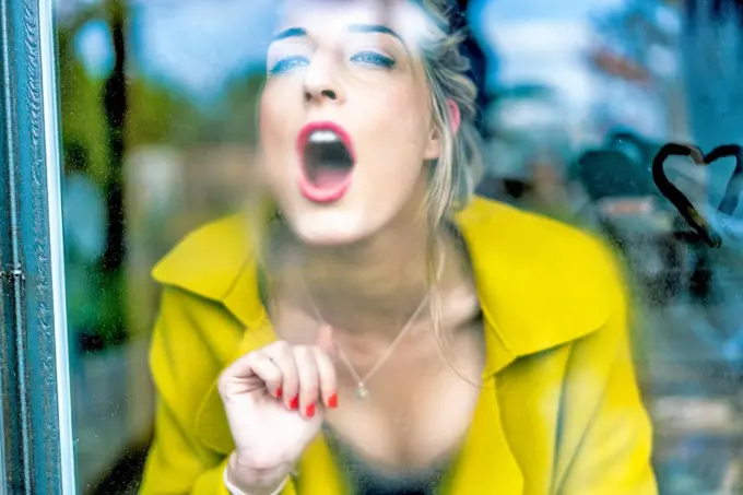 Woman breathing on a windowpane