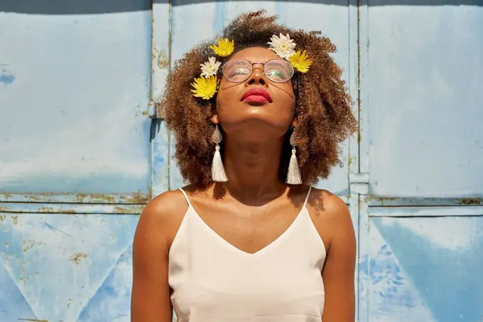 Portrait of young woman with red lips wearing glasses and flowers in her hair looking up