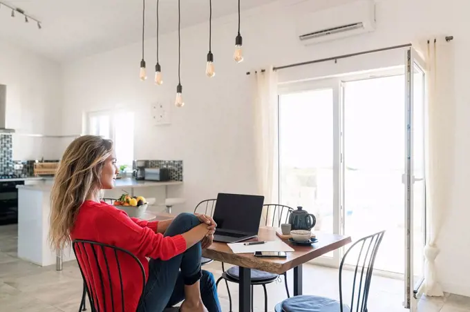 Woman using laptop on dining table in modern home