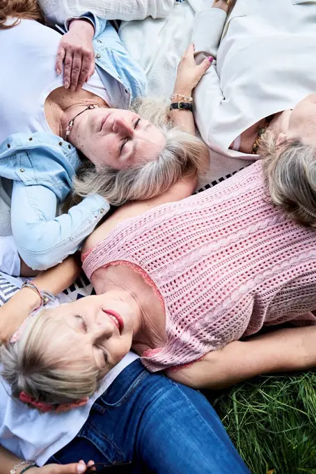 Top view of group of senior women lying in a meadow