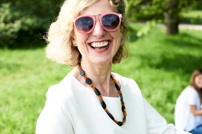 Portrait of happy senior woman wearing sunglasses in park