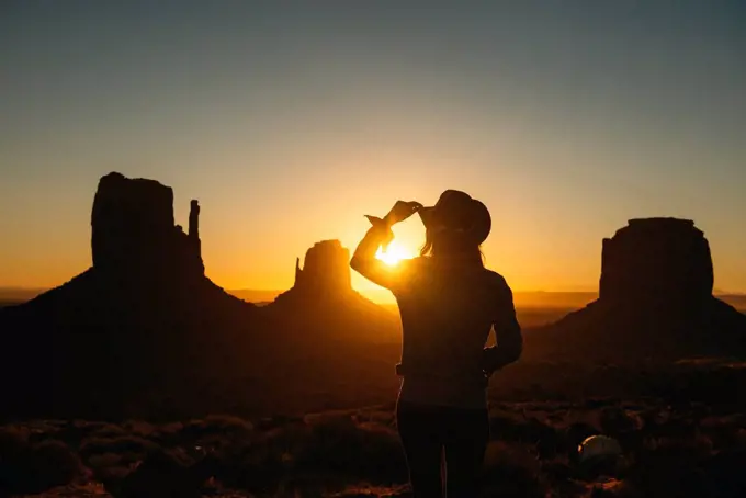 USA, Utah, Monument Valley, silhouette of woman with cowboy hat watching sunrise