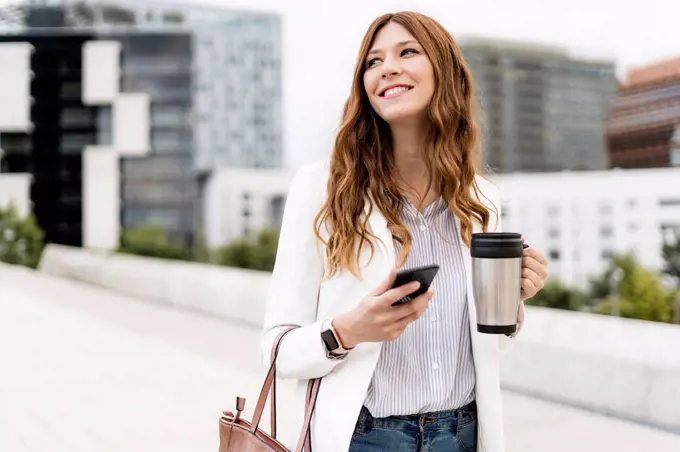 Young businesswoman commuting in the city, using smartphone