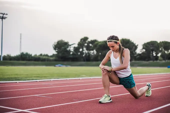 Female athlete doing warm-up exercises on tartan track